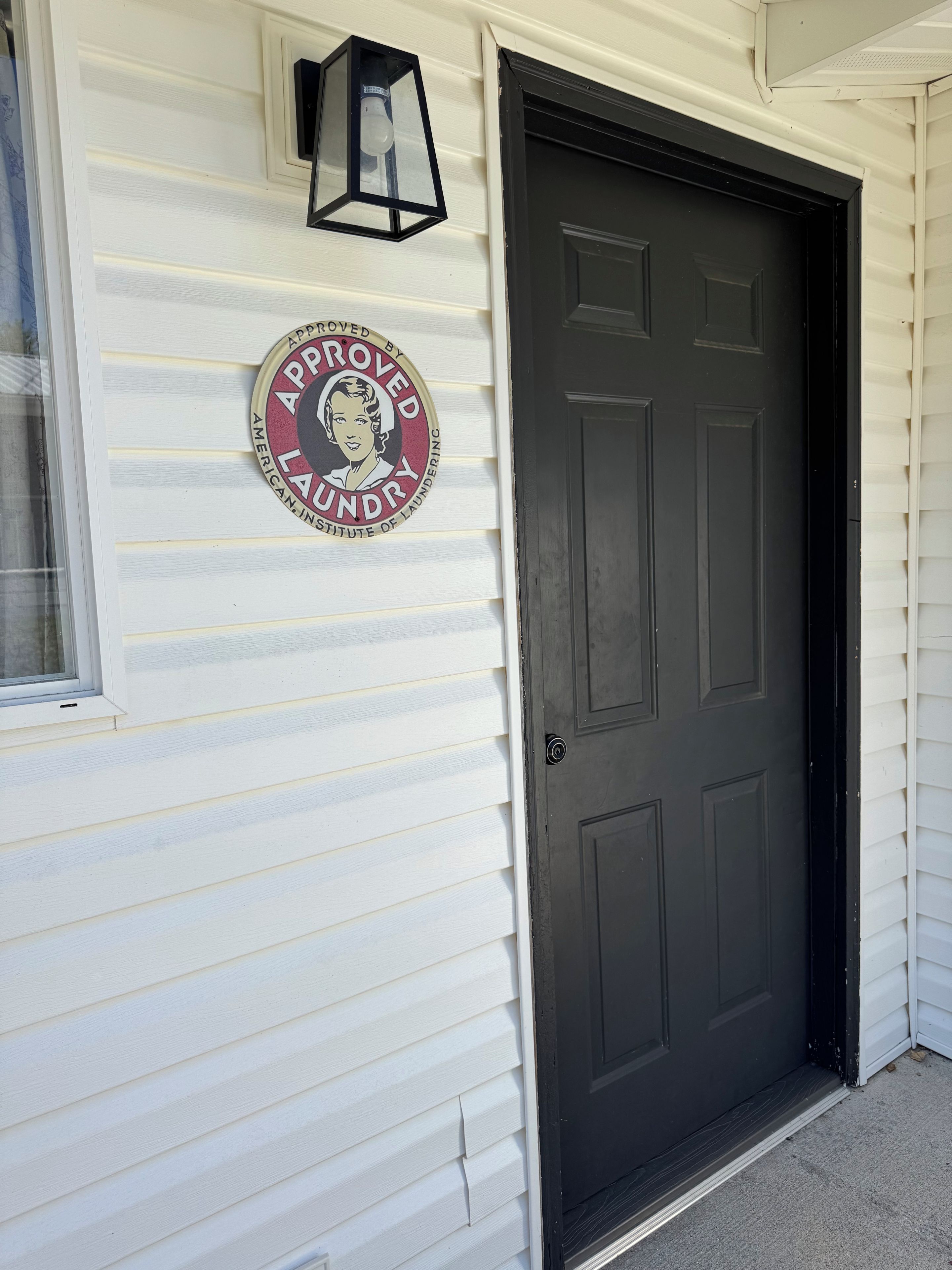 A house with a dark front door and a circular sign on the wall.