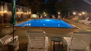 A swimming pool with lounge chairs and umbrellas, surrounded by a fence and trees. - Gidget at Villager- Pool,Resort Dock (Burnside)
