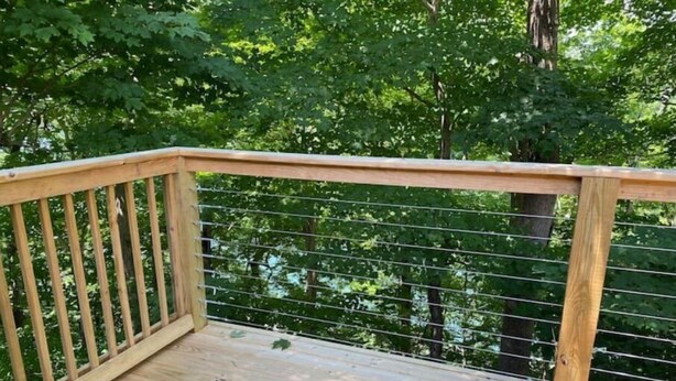 A wooden deck with a metal railing, surrounded by trees. - Gidget at Villager- Pool,Resort Dock (Burnside)
