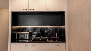 Une cuisine moderne équipée d’un four à micro-ondes encastré, d’une machine à café et d’une bouilloire.