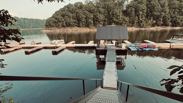 Um cais se estende por um lago calmo, com um pequeno edifício no final.