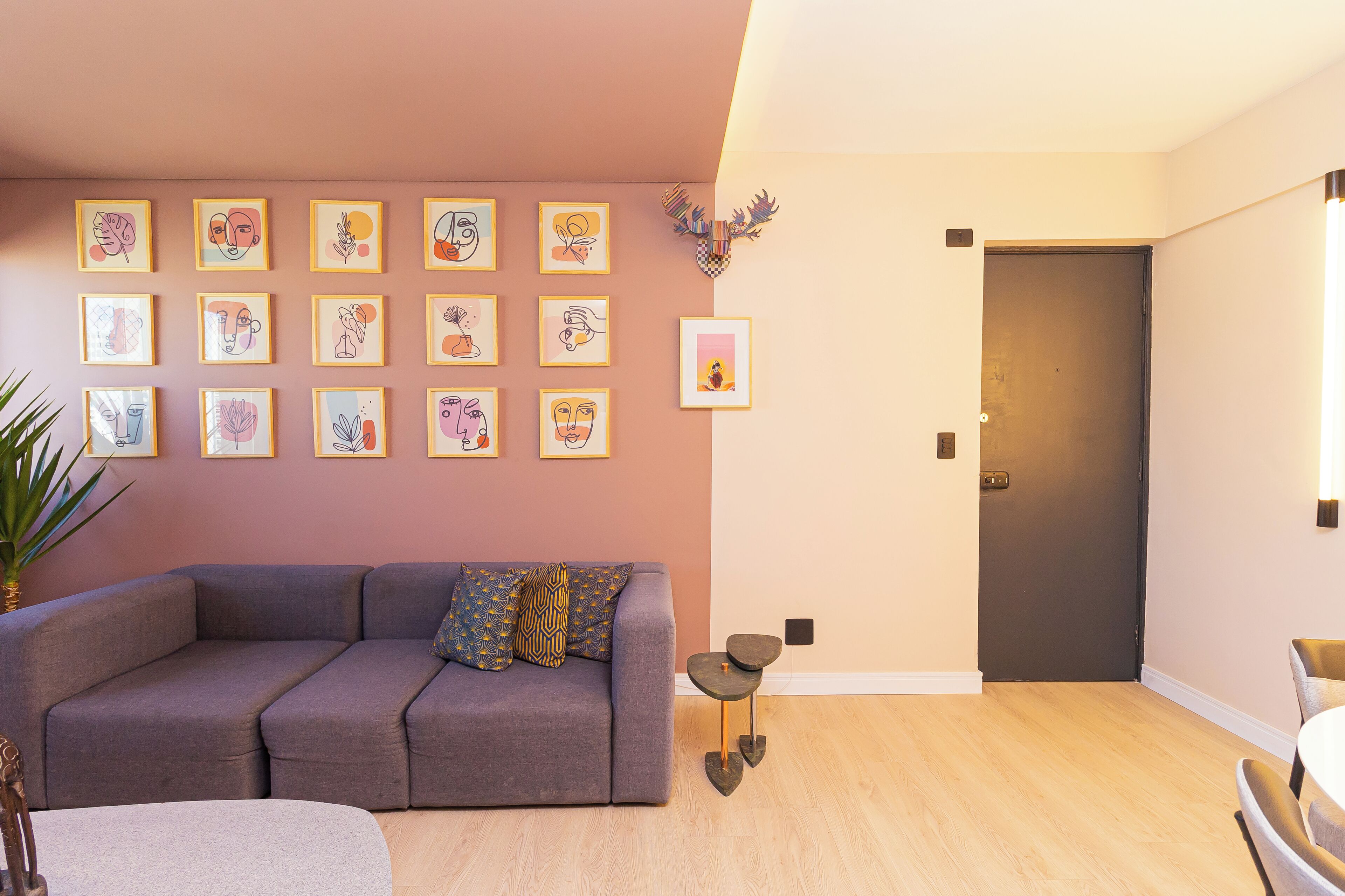 A modern living room with a grey sectional sofa, a small round table, and a wall decorated with framed abstract art.