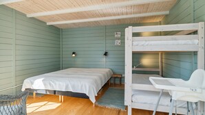 Ein Zimmer mit Etagenbett, einem Einzelbett, einem kleinen Tisch und zwei Wandlampen.