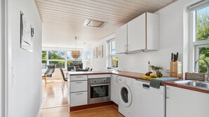 Eine moderne Küche mit weißen Schränken, einer Holz Arbeitsplatte, einem eingebauten Backofen und einer Waschmaschine.