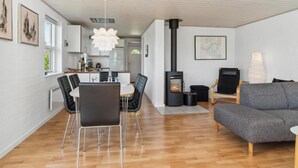 Ein zeitgemäßer Wohnbereich mit Essplatz, einer Couch, einem Kamin und einer Küche.