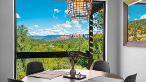 A dining area with a table, chairs, and a view of a mountainous landscape.