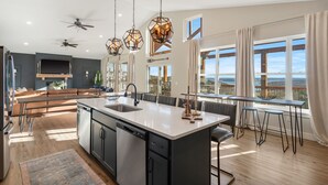 A modern kitchen with a central island, pendant lights, and a view of the outdoors. - Timeless Lake Views, Indoor Pool, Game Room, Hot tub, Firepit, Minutes from SDC (Branson)