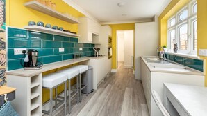 A modern kitchen with teal and white cabinets, a bar area with stools, and a window with a view.