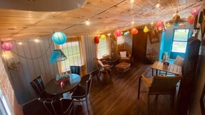 A cozy room with wooden floors, a dining area with chairs and a table, and a seating area with a sofa and chairs. - Kellerman’s at Villager-Pool, Resort Dock (Somerset)