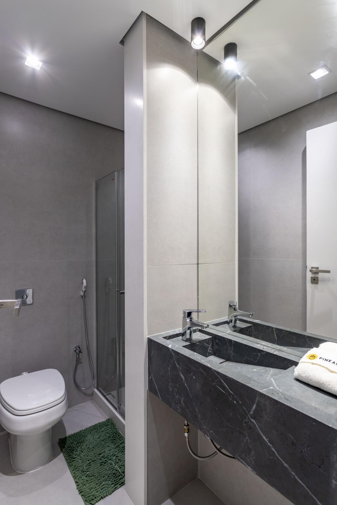 A modern bathroom with a large mirror, a shower, and a toilet.