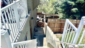 Un escalier menant à un espace extérieur abrité, doté d’une clôture en bois et d’une table avec des chaises.