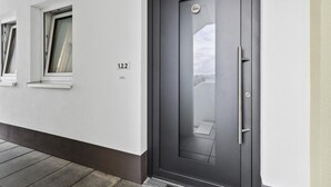 A modern exterior of a building with a dark grey door, a small window, and a number plate '1.2.2'. - GebirgsResort Winterberg (Winterberg)