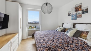 Une chambre à coucher avec un lit, une télévision, une fenêtre donnant sur un beau paysage et un luminaire suspendu.