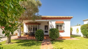 A house with a tiled patio, a small garden, and a clear blue sky.