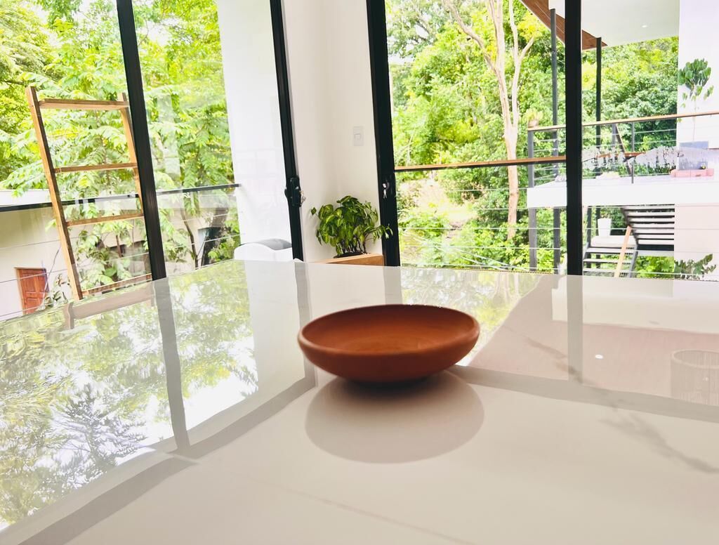 A modern interior with a large window, a white table, and a brown bowl.