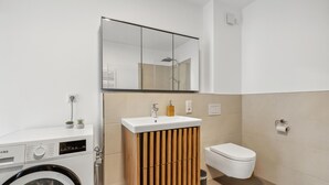 Ein modernes Badezimmer mit Waschmaschine, Waschbecken, Toilette und Spiegel.