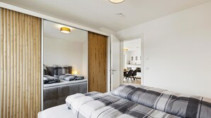 Ein modernes Hotelzimmer mit einem großen Bett, einer Couch, einer Holzwand und Blick in den Speisesaal.