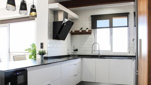 Eine moderne Küche mit weißen Schränken, einer schwarzen Arbeitsplatte und einem eingebauten Ofen. Über der Spüle befindet sich ein Fenster und auf der Arbeitsplatte ein Blumentopf.