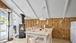 A cozy dining area with a wooden table and chairs, a black wood stove, and a white ceiling. - Amazing home in Hejls with WiFi (Hejls)