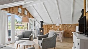 A cozy room with a fireplace, wooden walls, and a dining area. - Amazing home in Hejls with WiFi (Hejls)