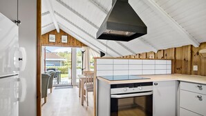 A modern kitchen with a built-in oven, a dishwasher, and a large window overlooking a garden. - Amazing home in Hejls with WiFi (Hejls)