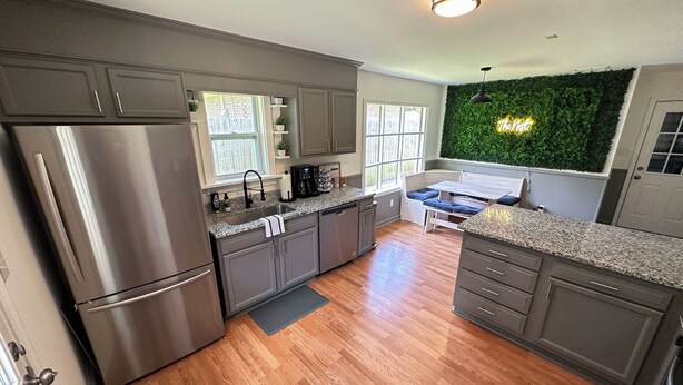 Una cocina moderna con refrigerador integrado, encimeras de granito y un comedor con banco.
