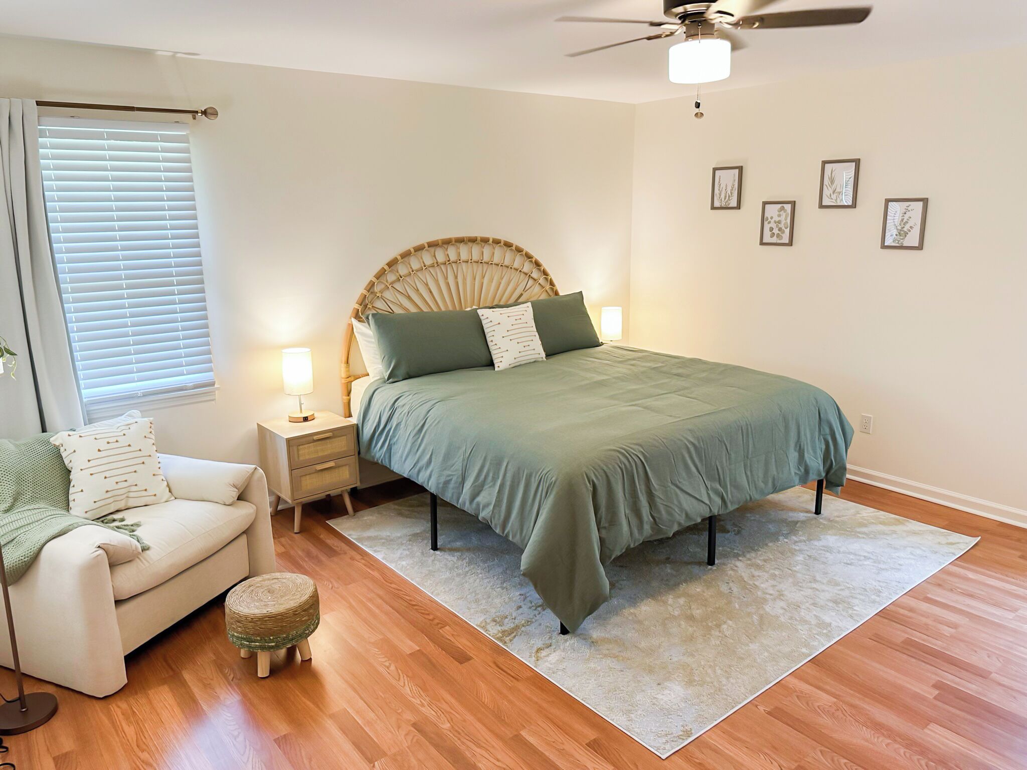 A bedroom with a bed, bedside table, lamp, and a small stool.