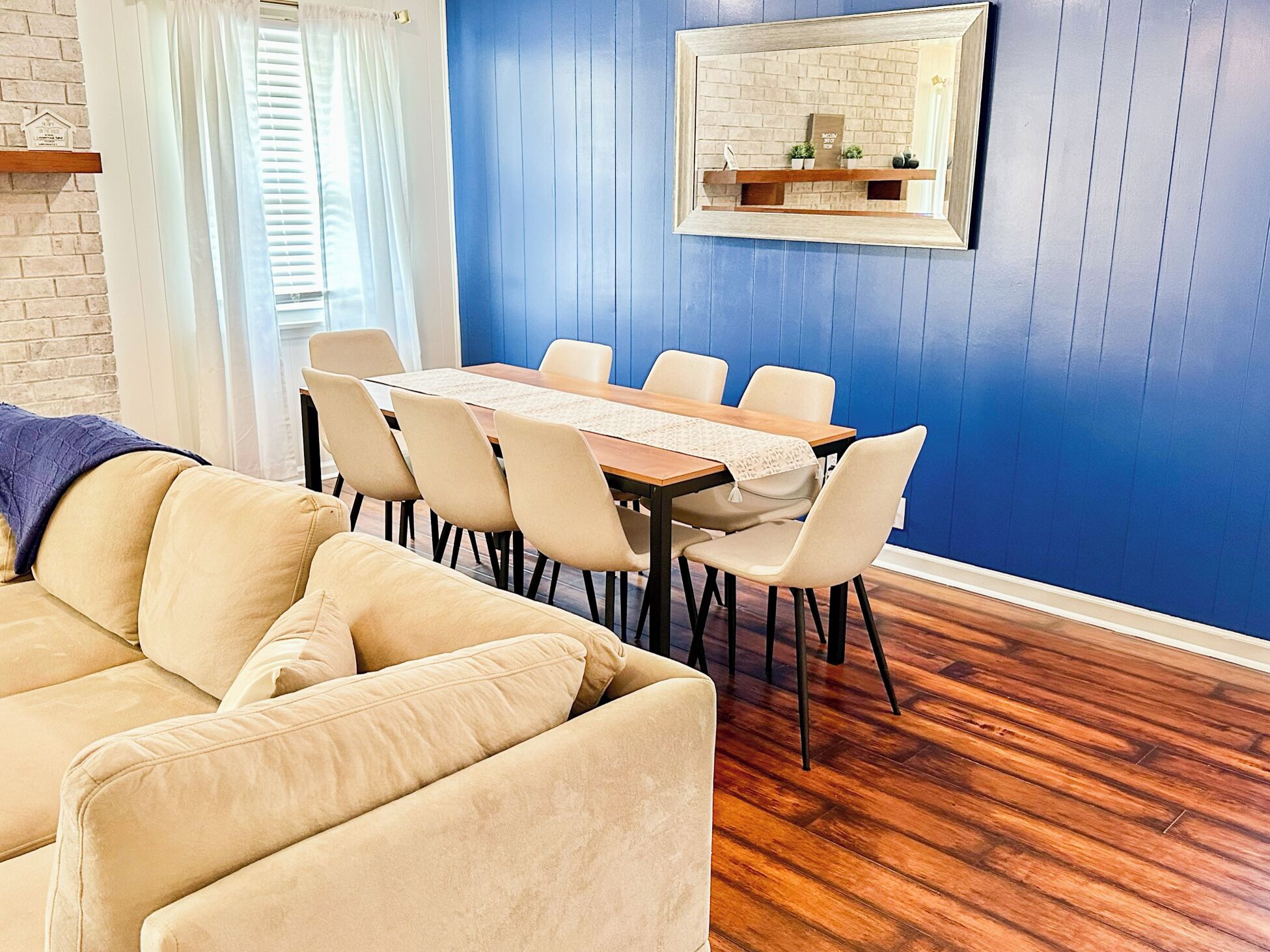 A dining area with a wooden table and chairs, a blue wall, and a wooden floor.