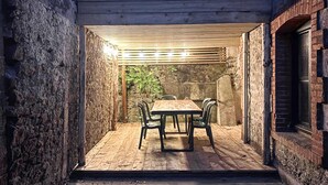An outdoor patio with a wooden table and chairs, surrounded by stone walls and a wooden pergola. - Lovely home in Saint-Vaast-la-Hougue with WiFi (Saint-Vaast-la-Hougue)