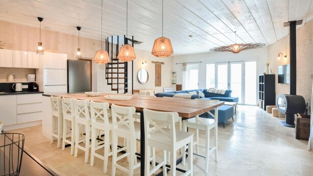 A modern kitchen with a wooden island, white chairs, pendant lights, and a large window. - Lovely home in Saint-Vaast-la-Hougue with WiFi (Saint-Vaast-la-Hougue)
