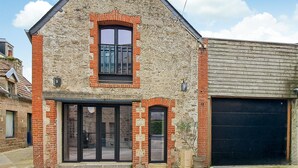 A two-story building with a stone facade, a large garage door, and a prominent entrance with glass doors. - Lovely home in Saint-Vaast-la-Hougue with WiFi (Saint-Vaast-la-Hougue)
