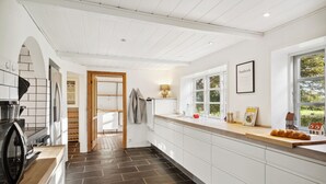 Een moderne keuken met witte kasten, een houten aanrechtblad en uitzicht op het landschap door een raam.