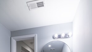 Un baño con tocador blanco, espejo redondo y argolla para toallas.