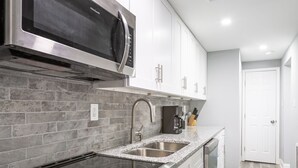 Una cocina moderna con electrodomésticos de acero inoxidable, encimeras de granito y salpicadero de azulejos.
