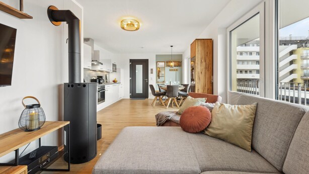 Ein modernes Wohnzimmer mit einer Couch, einem Fernseher, einem Kamin und einem Essbereich mit Tisch und Stühlen.