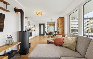 A modern living room with a sofa, a TV, a fireplace, and a dining area with a table and chairs. - Cozy apartment in Winterberg with WiFi (Winterberg)