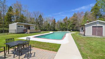 Enjoy a refreshing swim in the pool surrounded by a patio area with a table and chairs.