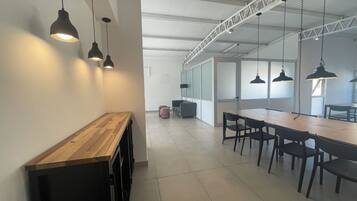 Un espacio de oficina moderno con una larga mesa de madera, sillas negras e iluminación colgante.