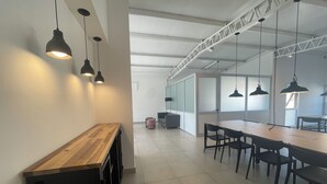 A modern office space with a long wooden table, black chairs, and pendant lighting.