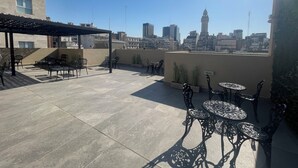 A rooftop terrace with outdoor seating, a pergola, and a city skyline view.