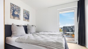 A modern bedroom with a large bed, striped pillows, and two wall art pieces of deer. - GebirgsResort Winterberg (Winterberg)