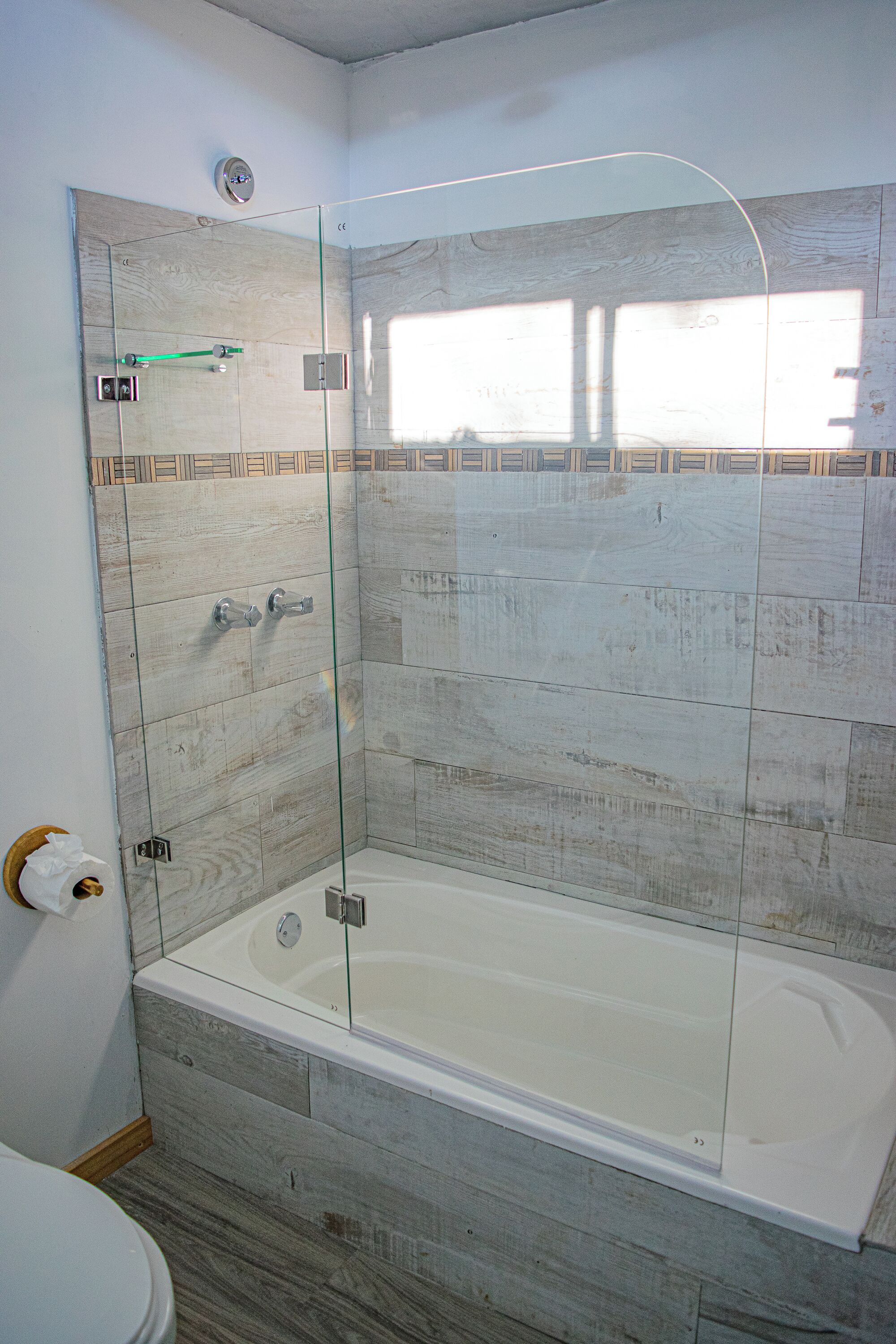 Une salle de bain avec une douche à parois de verre, une baignoire blanche et des toilettes.