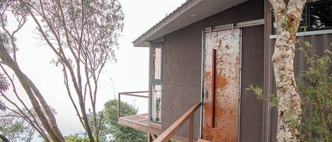 Un edificio moderno con terraza de madera, ventanas grandes y una puerta.