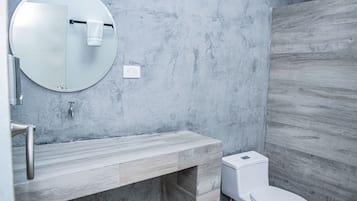 A modern bathroom with a round mirror, a wooden vanity, a toilet, and a wall-mounted towel rack.