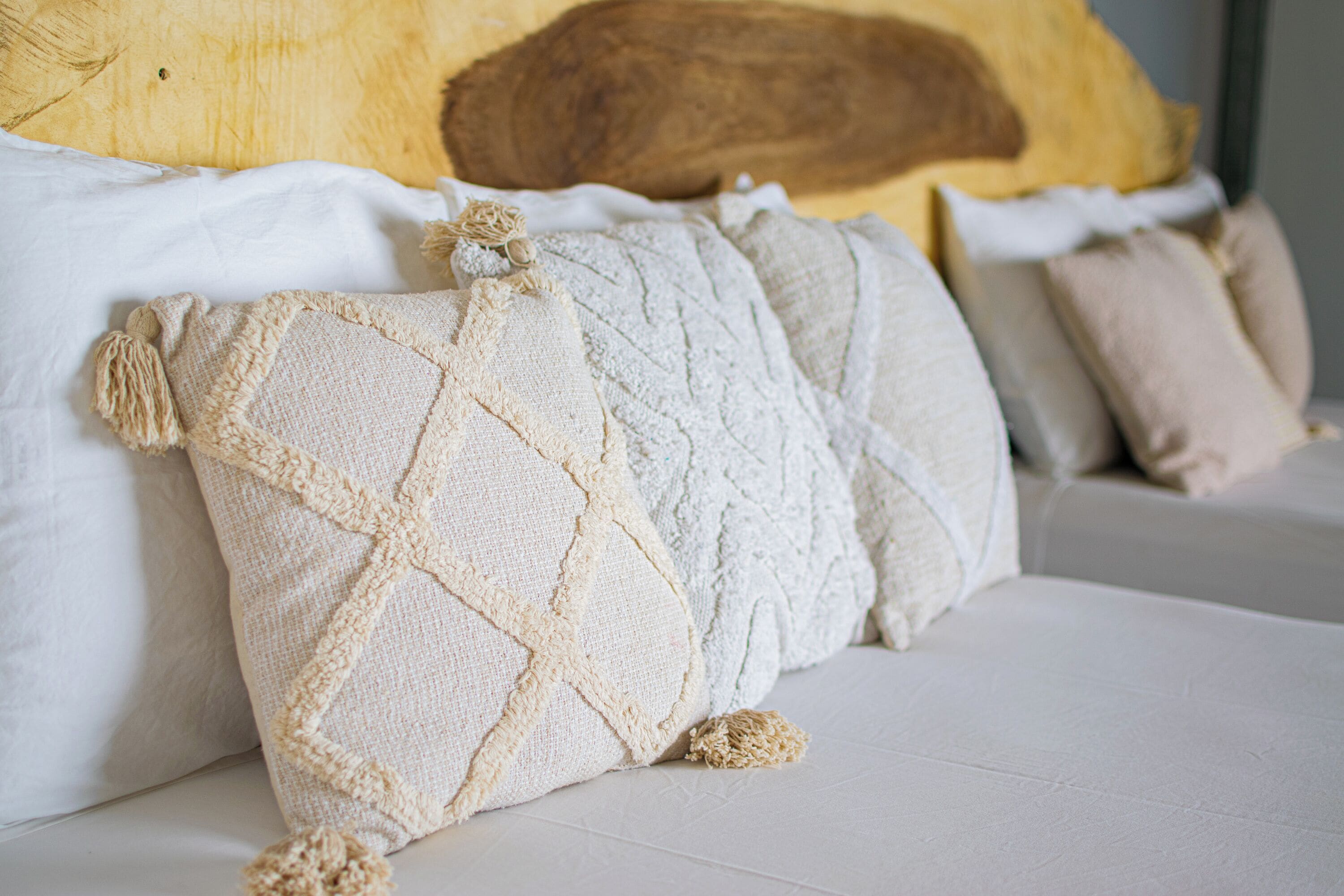 A bed with multiple pillows, a wooden headboard, and a white mattress.