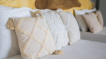 A bed with multiple pillows, a wooden headboard, and a white mattress.