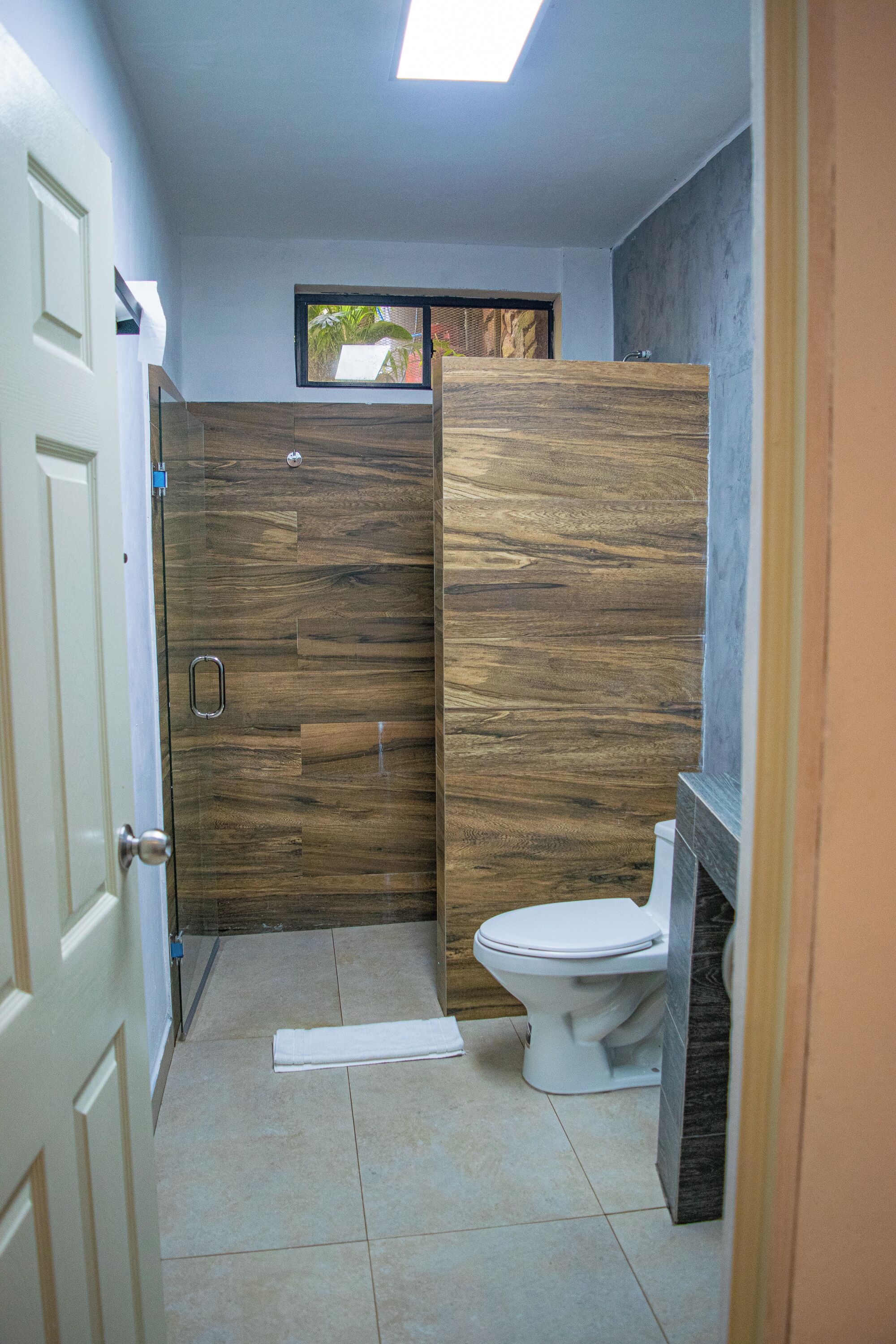 Un baño con tocador de madera, inodoro y zona de ducha.