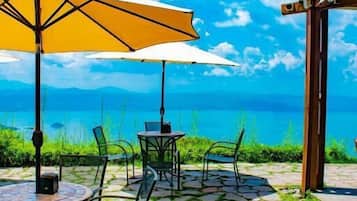 Un patio al aire libre con suelo de piedra, sillas de metal y un paraguas amarillo.