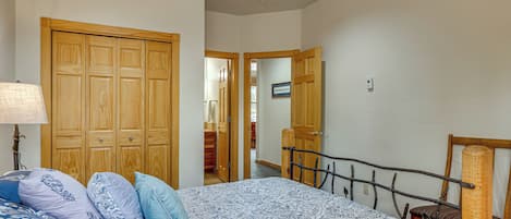 A bedroom with a bed, a wooden wardrobe, a nightstand, and a lamp.
