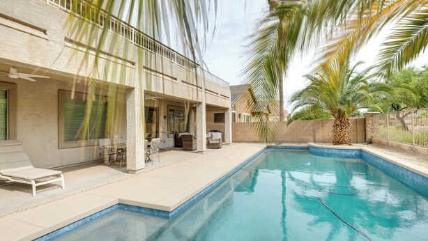 A swimming pool with a covered patio area, a ceiling fan, and a palm tree. - Maricopa Oasis w/ Game Room + Community Perks! (Maricopa)